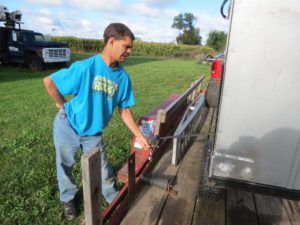Mike uses boat trailer rollers to easily slide his ramps on the the trailer with one arm. Self-retracting tie-down straps are bolted to the side of the trailer so Mike can tie down his ramps and mower/leaf vacuum with one hand.