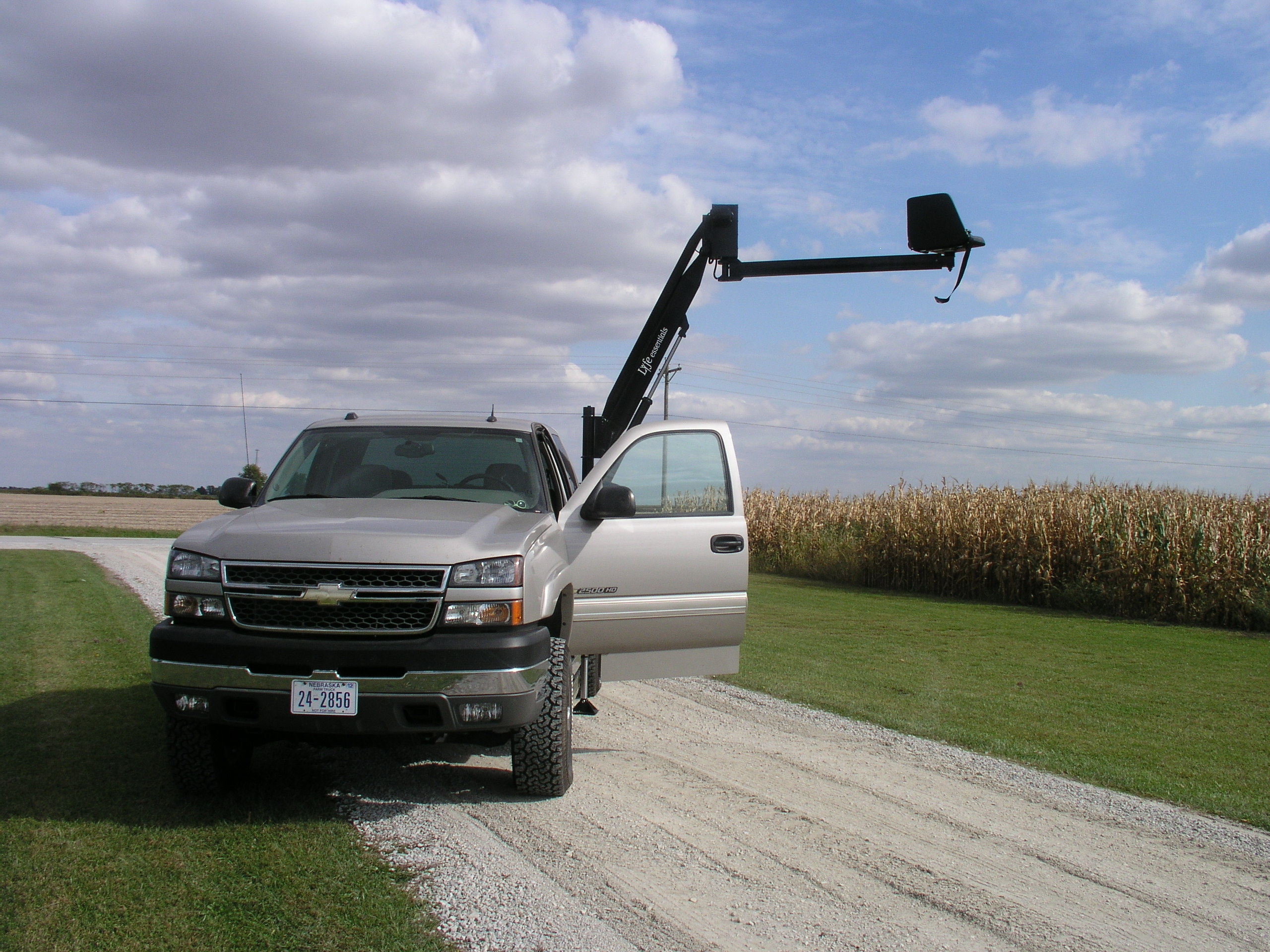 Manlift mounted on pickup truck extended 12 feet high and 14 feet to the side so a worker who cannot climb can access large equipment and tall places.