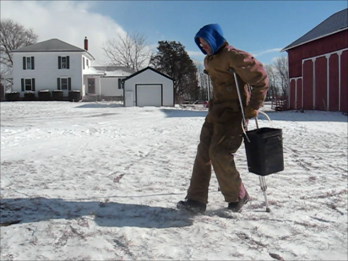 Handicapped farmer carrying a bucket.