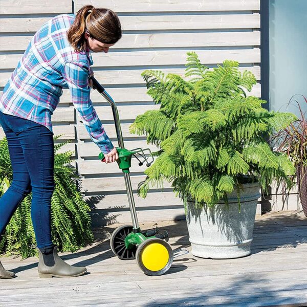 A lady using her dolly to lift her garden pot.