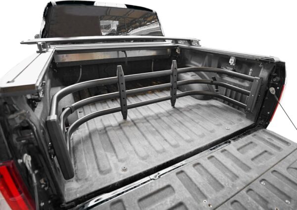 A black pickup truck with an extended tailgate extender folded into the bed of the pickup.