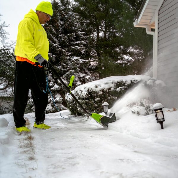 A person clearing the walkway to a house using the electric snow shovel.