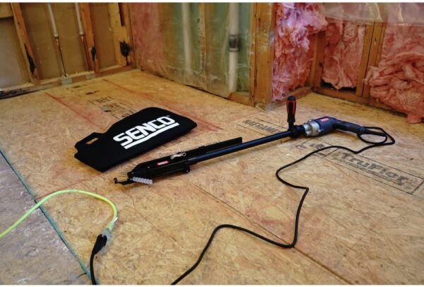 A Superdrive Collated Screwdriver 20" Extension laying on the floor plugged into an outlet in a room that is under construction